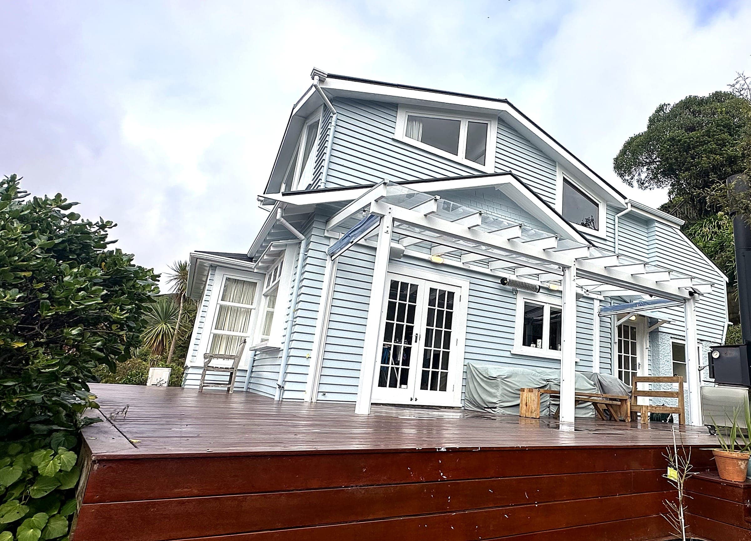 A repainted villa with pale blue weatherboards and white trim, above a timber deck