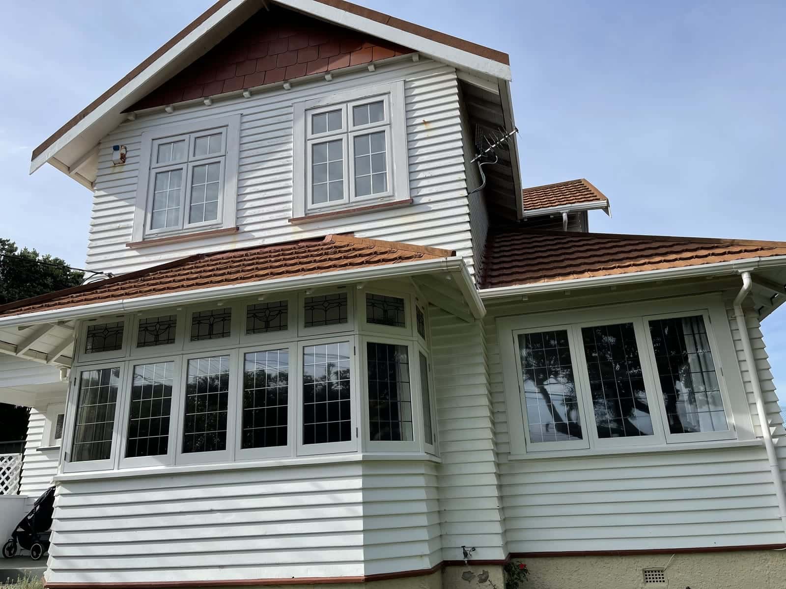 A two-storey villa with white weatherboards, leadlight bay windows and a tiled roof